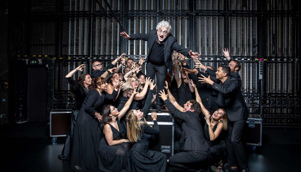 Photo de groupe du Chœur de chambre Mélisme(s) où Gildas Pungier, directeur, est au centre et mime de sauter, entourés des membres du chœur.