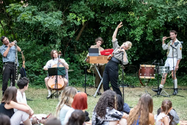 Femme chantant devant une foule, petit orchestre au second plan