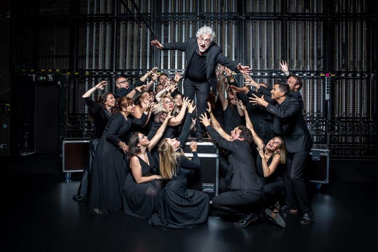 Photo de groupe du Chœur de chambre Mélisme(s) où Gildas Pungier, directeur, est au centre et mime de sauter, entourés des membres du chœur.